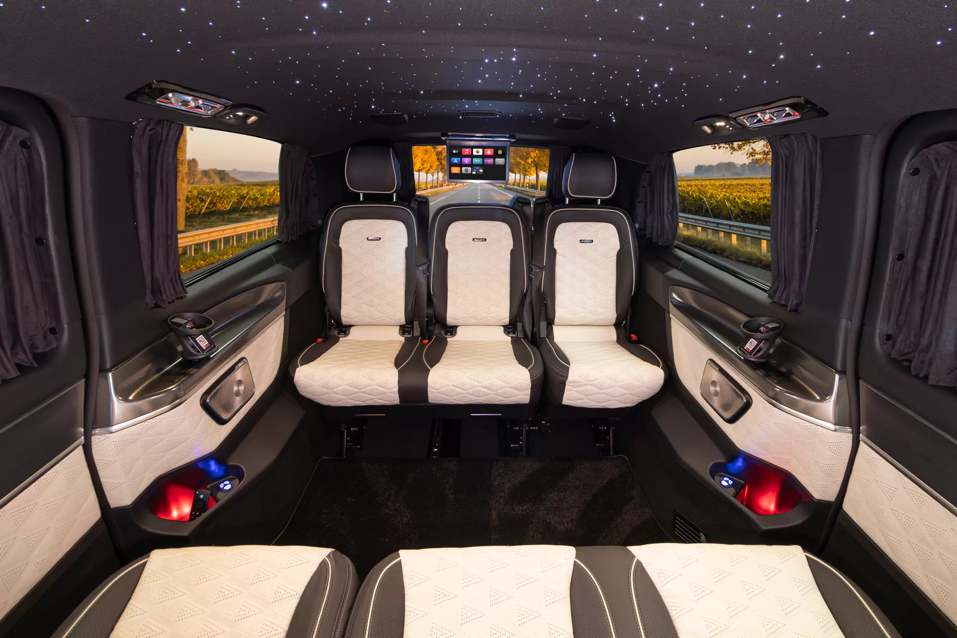 Luxury vehicle interior with white and black seats, starry ceiling lights, and a central screen showing apps.