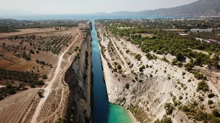 Aerial view of a deep narrow canal with clear water cutting through rocky cliffs in a dry landscape.