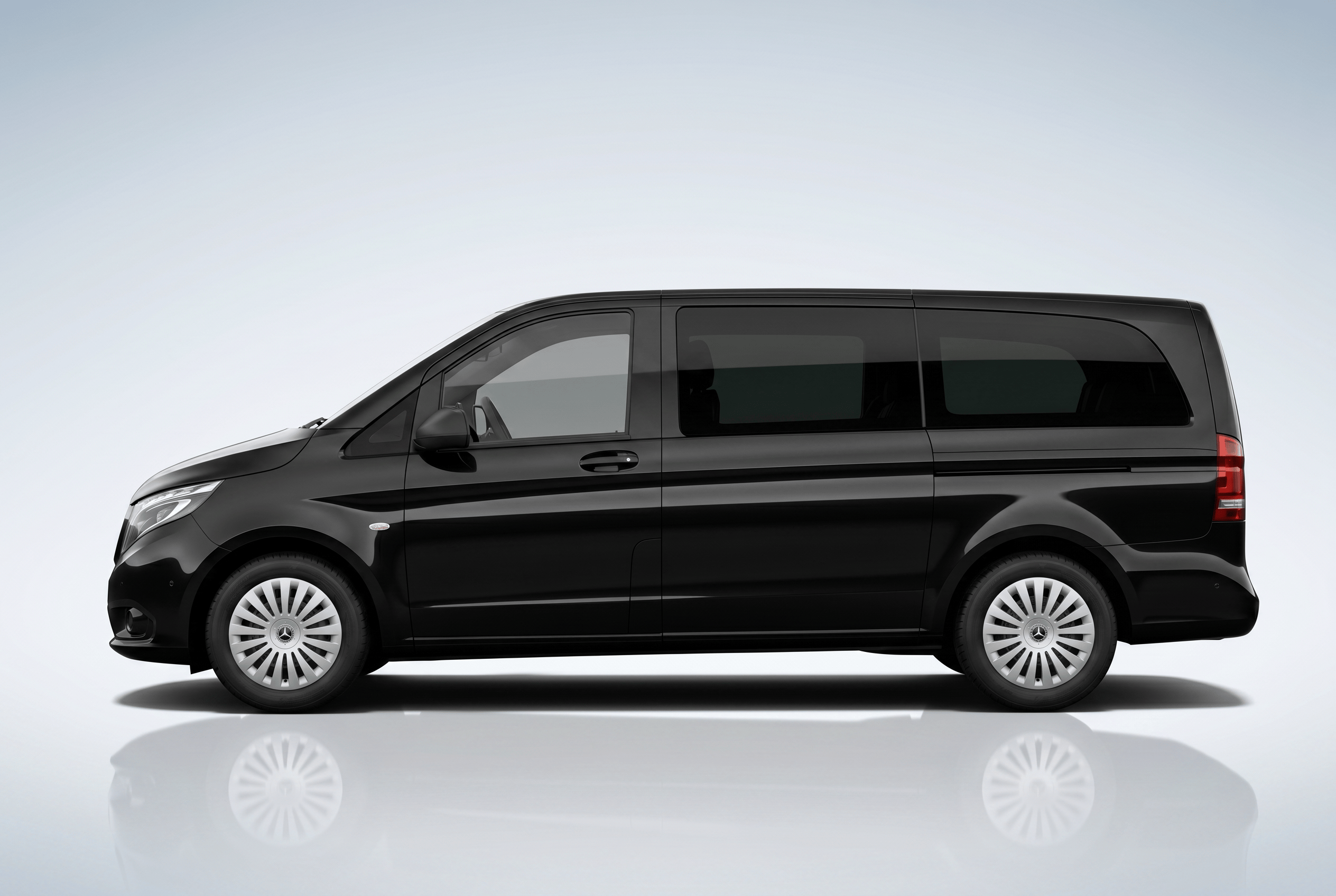 Side view of a sleek black modern van with tinted windows on a light background.