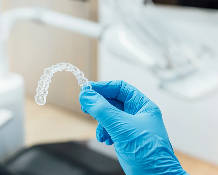 A Love Teeth dentist holding up a clear Invisalign aligner