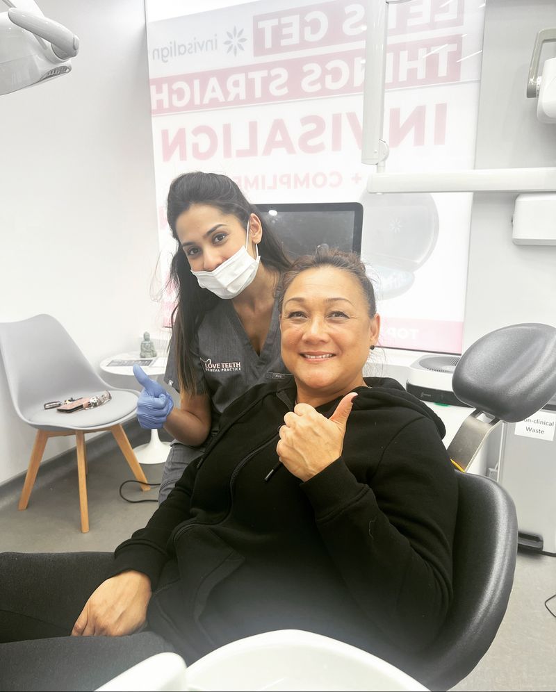 A smiling Love Teeth patient giving a thumbs up in the dental chair with her dentist