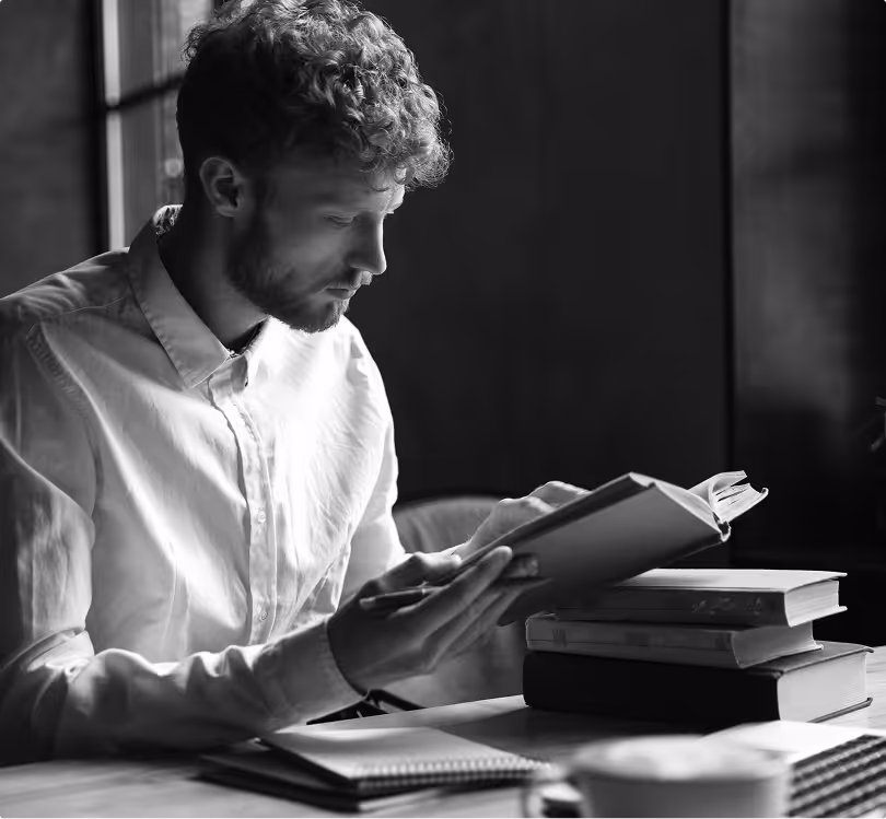 A black and white image of a young man studying and reading books