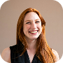 A smiling woman with a long red ginger hair on a beige background