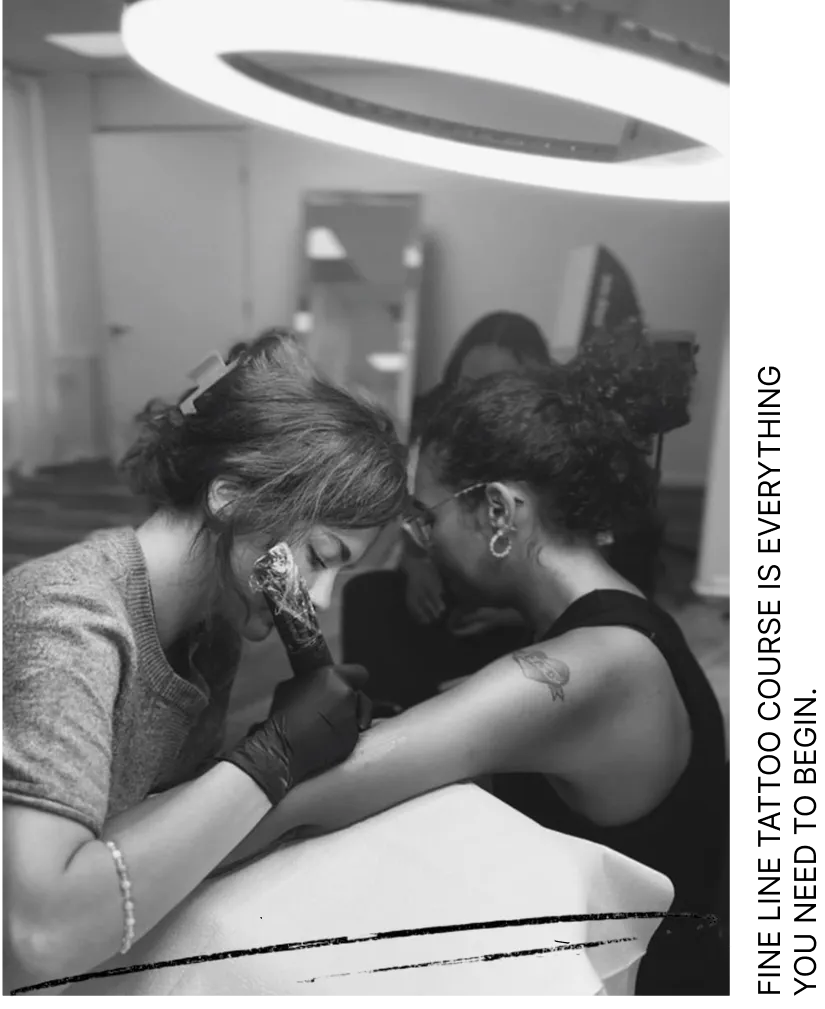 Tattoo artist wearing gloves working on a tattoo on a woman's upper arm in a studio with ring light.