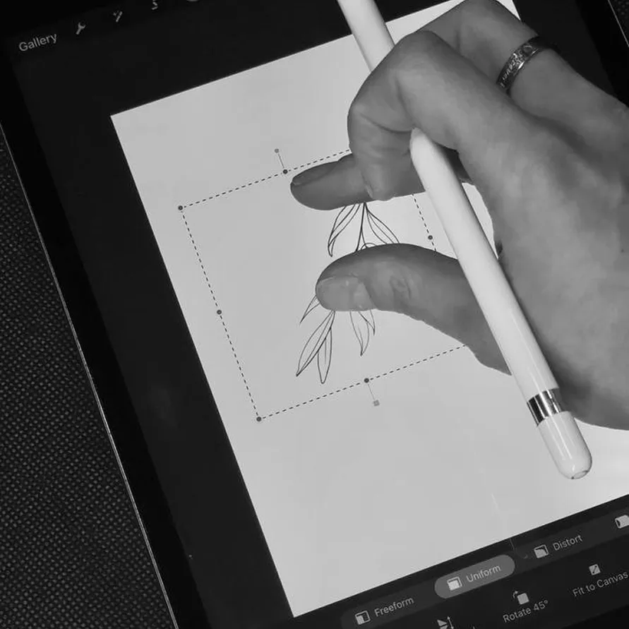Hand holding a stylus and pinching a digital floral drawing on a tablet screen.