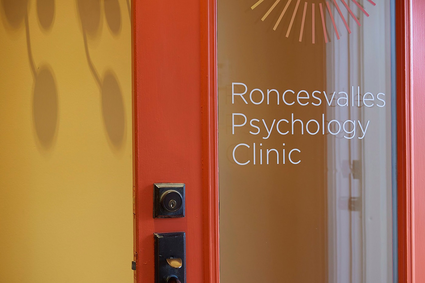Glass door with Roncesvalles Psychology Clinic text and a red frame with a black door lock.