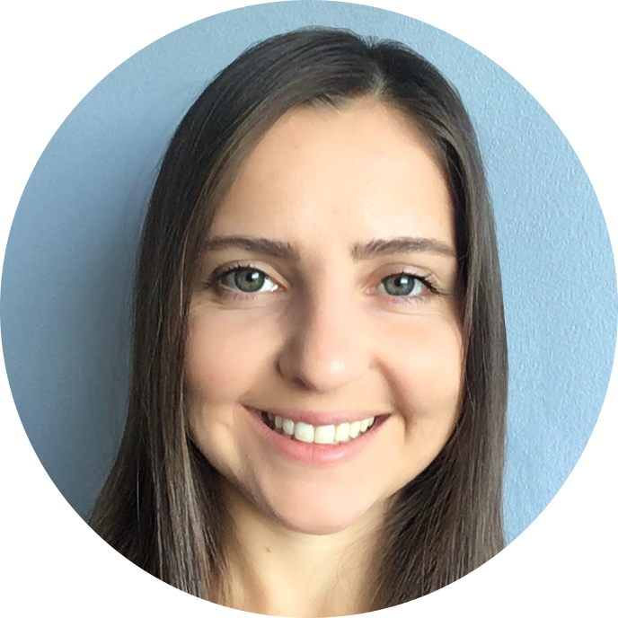Smiling woman with long brown hair and blue eyes against a light blue background.