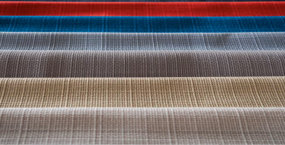 Close-up of folded fabric layers in red, teal, gray, brown, beige, and light gray colors.