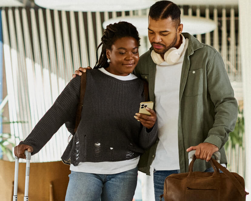 Couple looking at their phone with suitcases