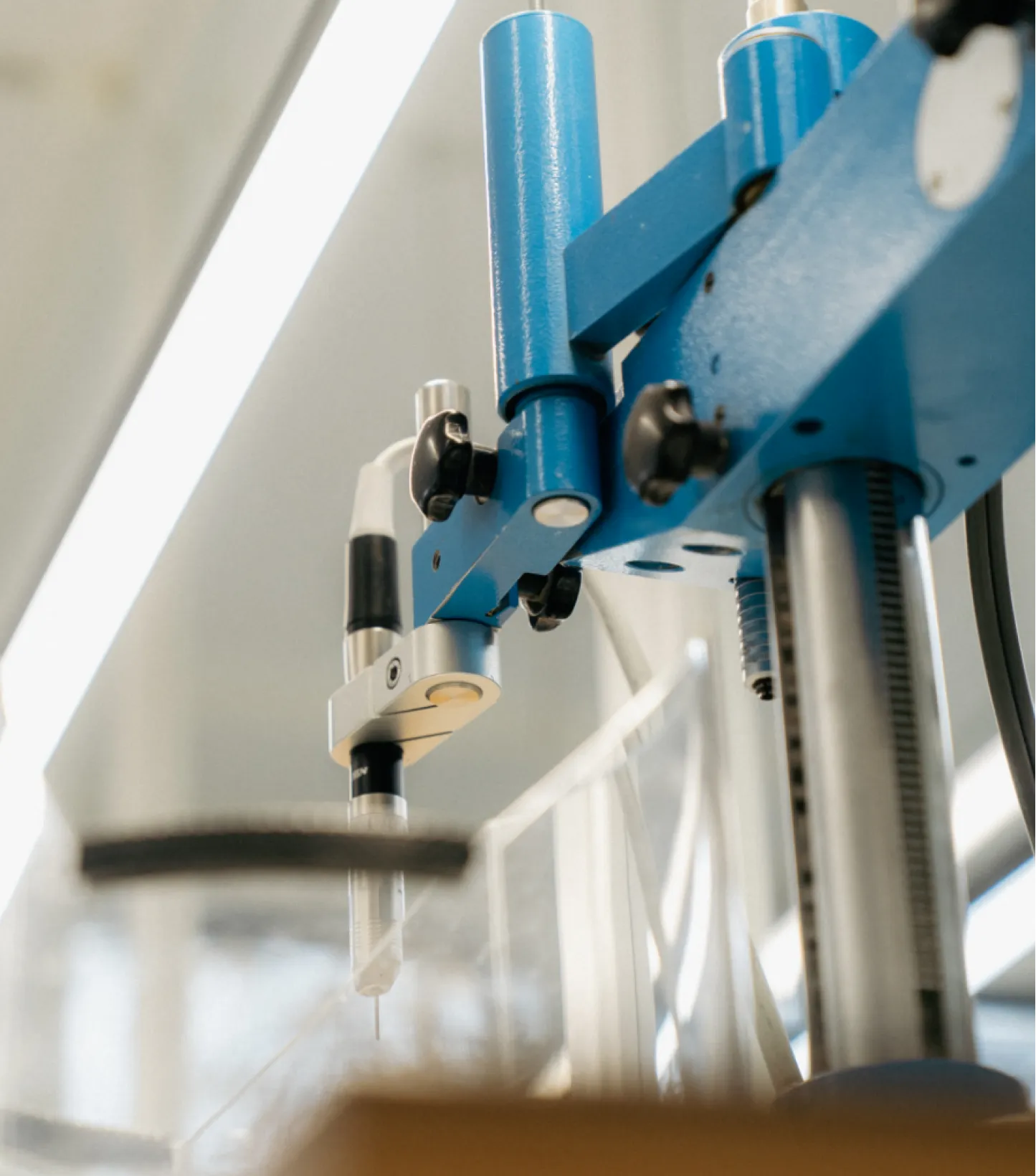 Nahaufnahme eines blauen Laborroboters mit einer feinen Nadelspitze in einem Laborumfeld.