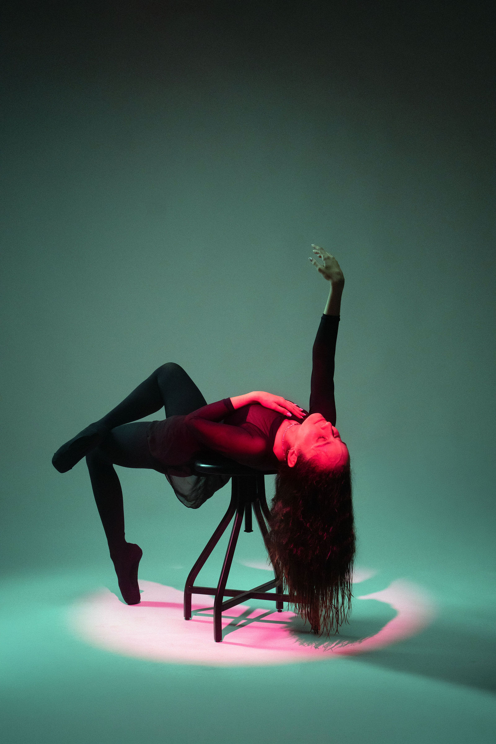 Andreina posed across a studio stool in green and red lighting