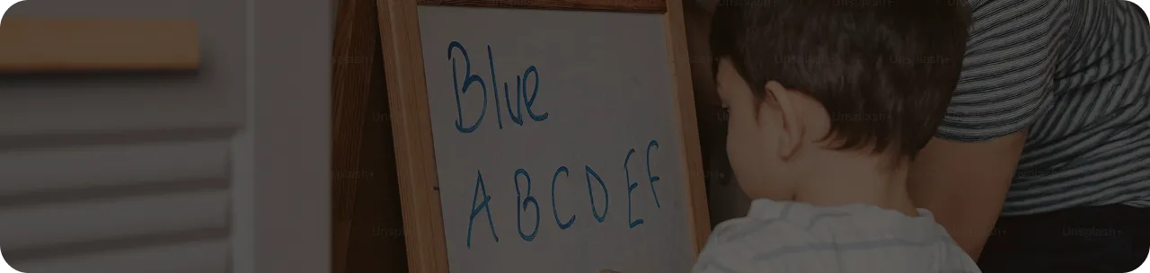 Child writing letters A to F on a whiteboard with the word 'Blue' written above them.