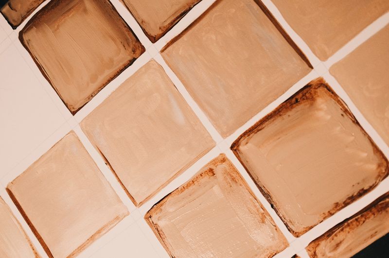 Close-up of square brown tiles with varied shading and a matte finish arranged in a grid pattern.