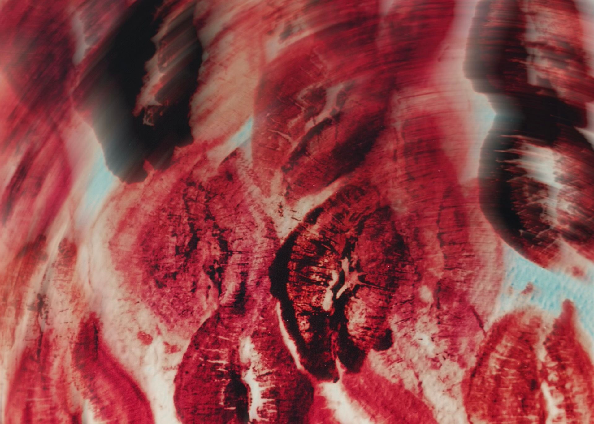 Close-up of red and black abstract patterns resembling wood grain texture with blurred edges.