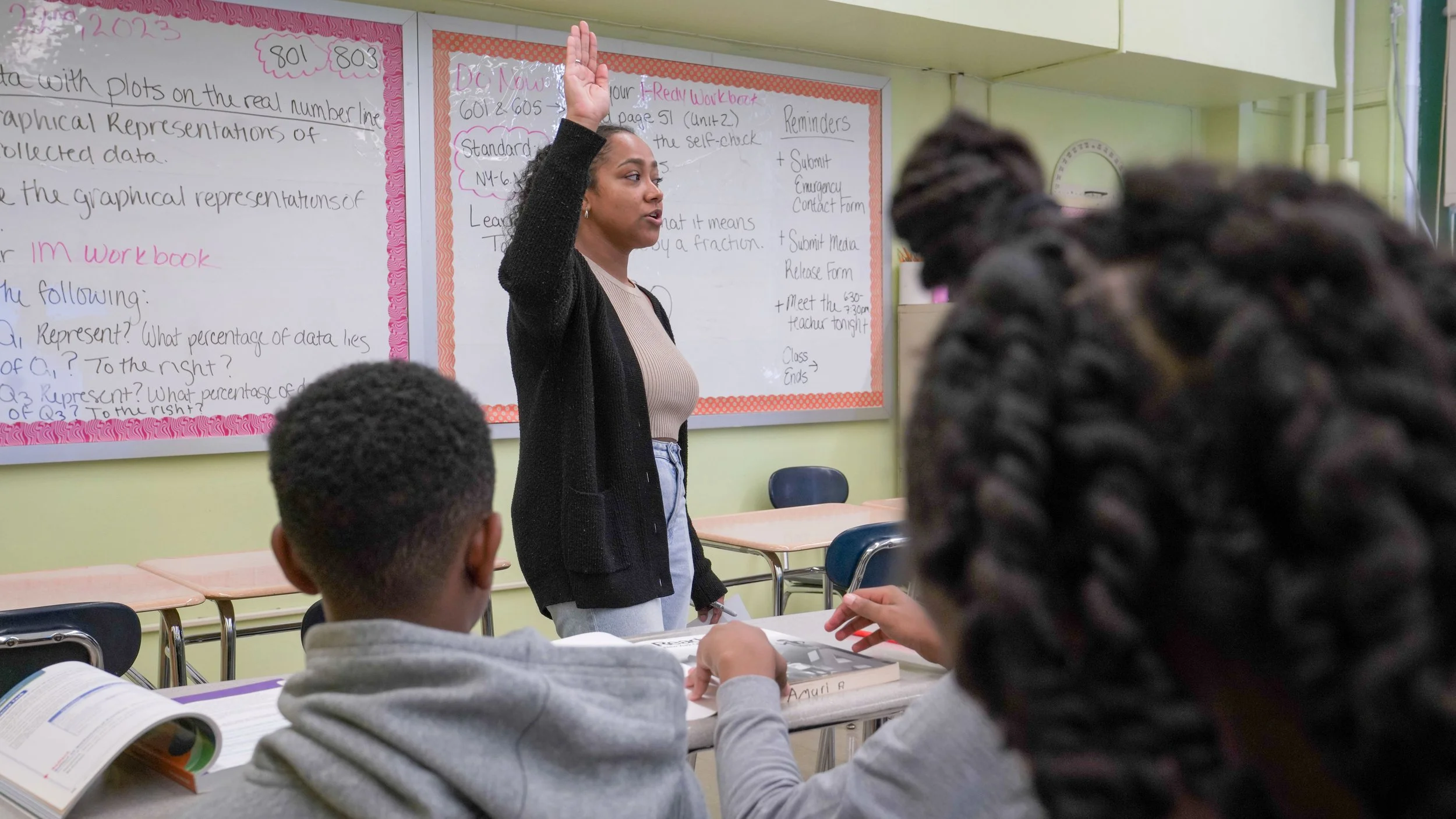 Teacher raising her hand and speaking to students in a classroom
