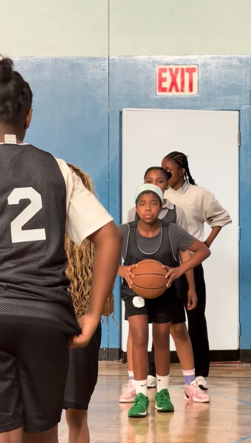 Young basketball player holding a ball in a gym with teammates 