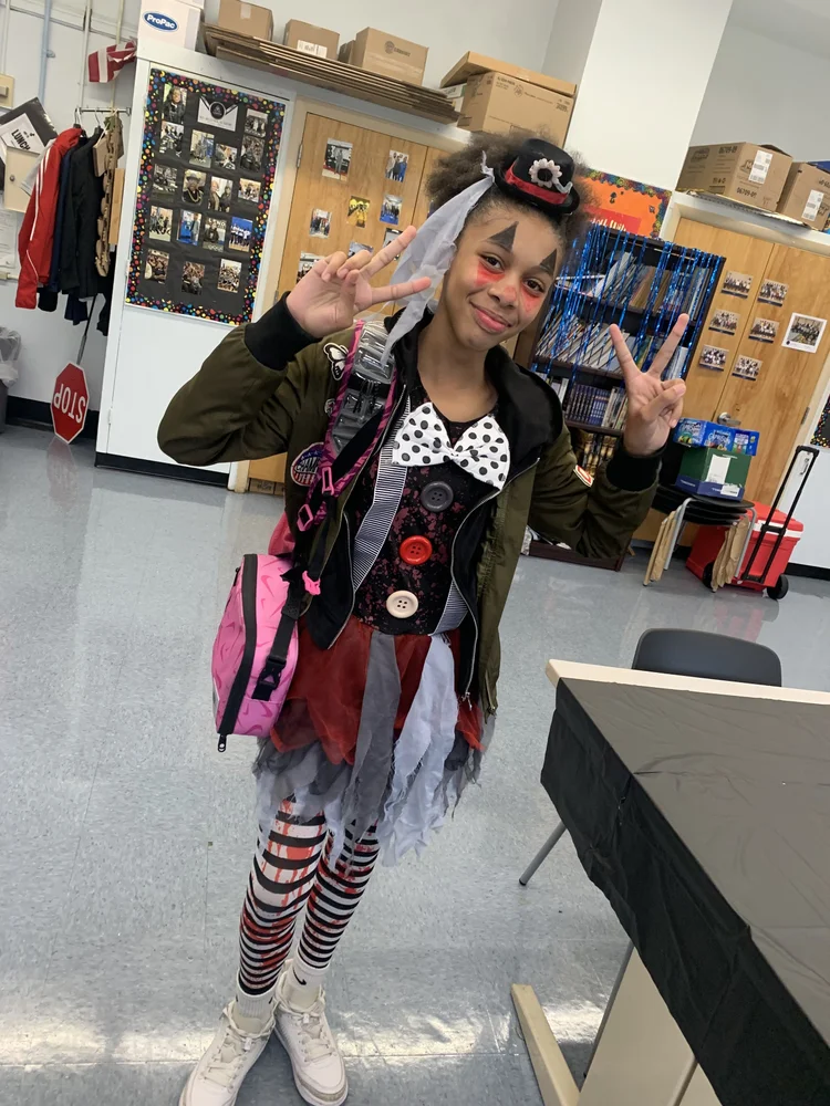 Smiling young girl in clown costume with face paint.