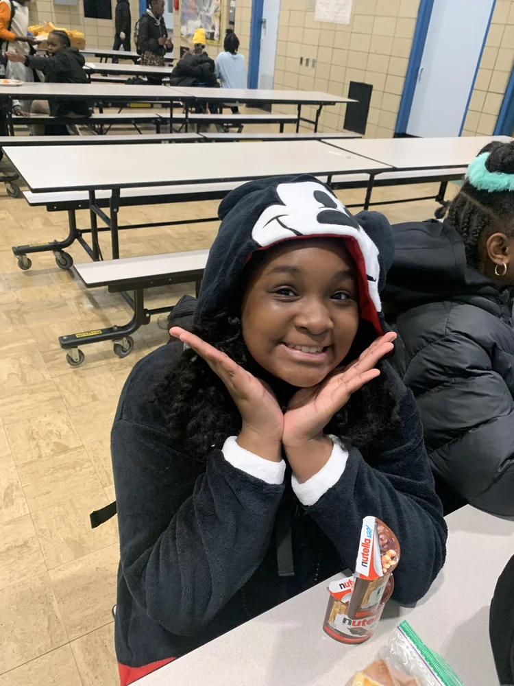 Smiling girl wearing a black Mickey Mouse hoodie.