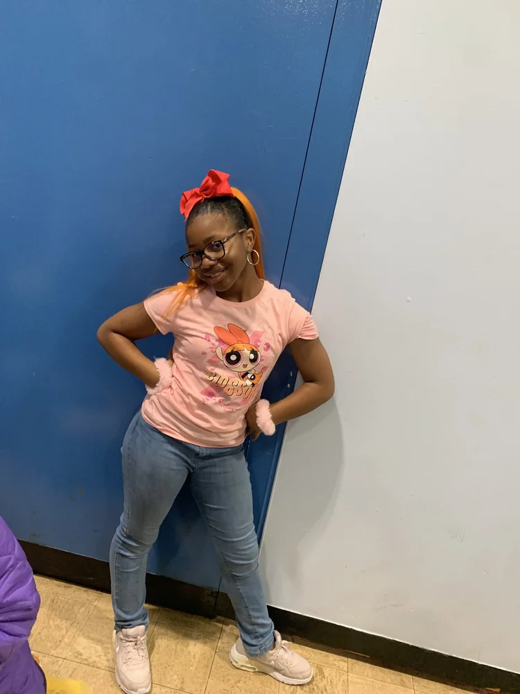 Young girl with orange hair and red bow wearing glasses