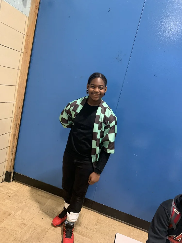 Smiling young person standing indoors against a blue wall