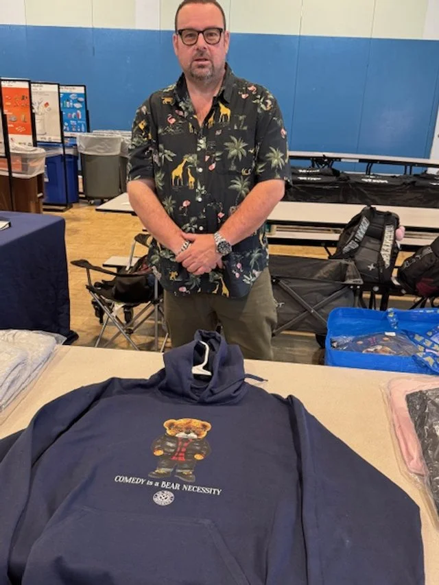Man wearing glasses and a black shirt with giraffe and palm tree prints.