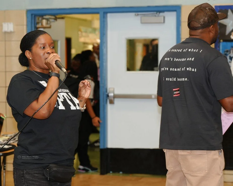 Woman speaking into a microphone indoors with a man 