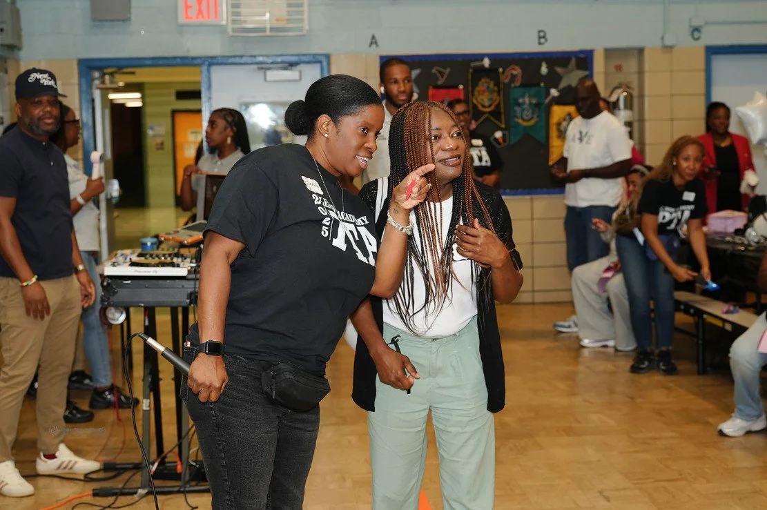 Two women smiling and interacting in a lively indoor.