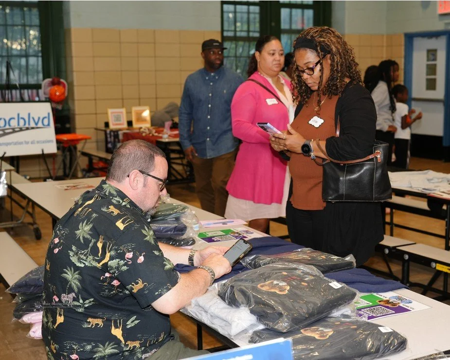 Man sitting at a table with folded clothing and pamphlets