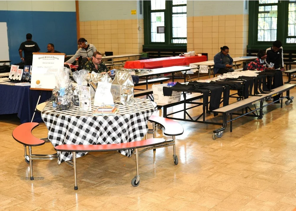 Indoor event with tables covered in black and white checkered cloth displaying various gift baskets and items