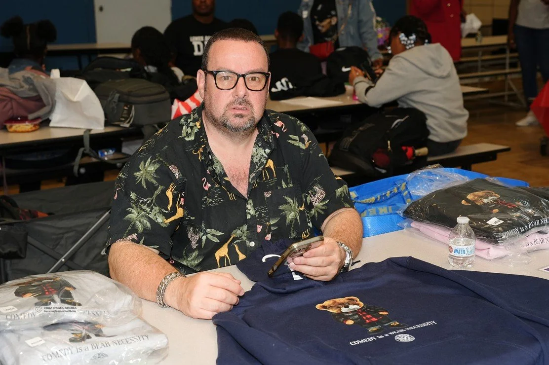 Man wearing glasses and a patterned shirt sits at a table 