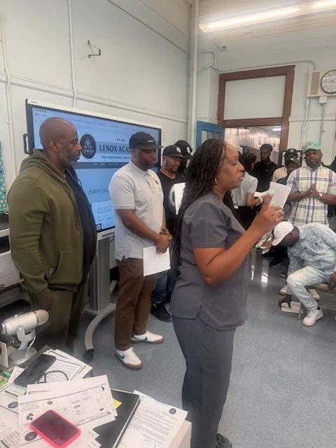A woman speaking and holding papers in a classroom