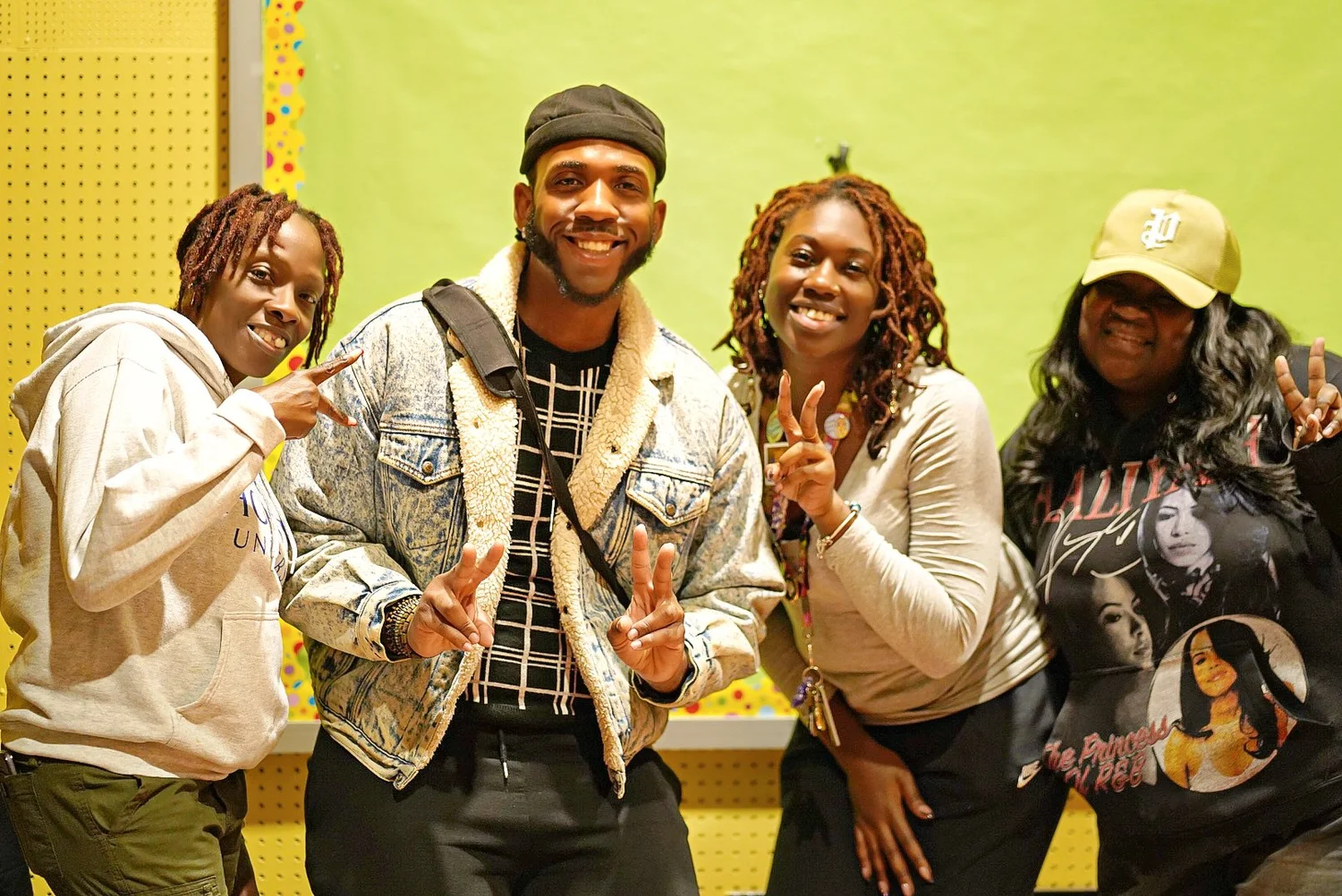 Four young adults smiling and posing with peace