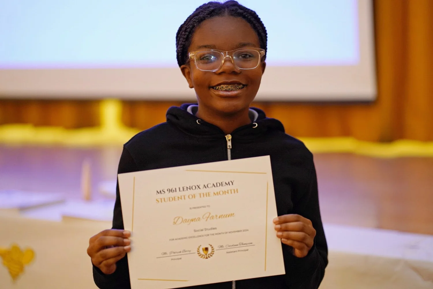 Student smiling and holding a Student of the Month certificate 
