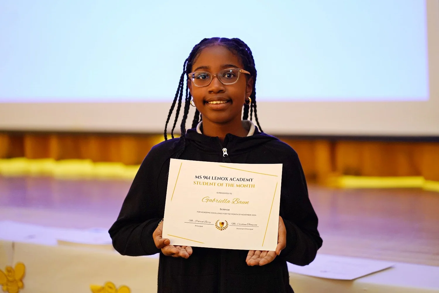 Smiling girl with braided hair and glasses holding