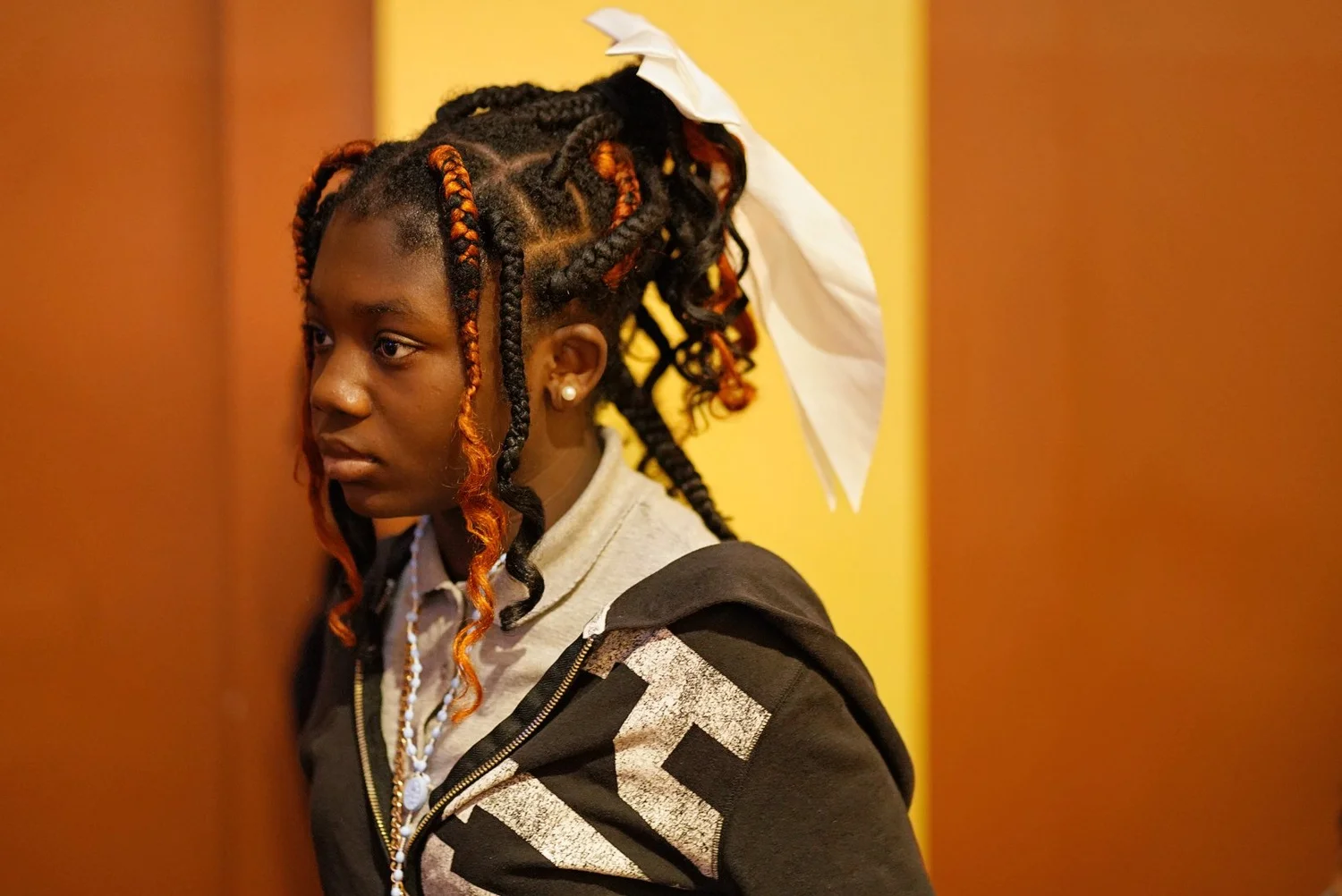 Young woman with black and orange braided hair tied with a white ribbon