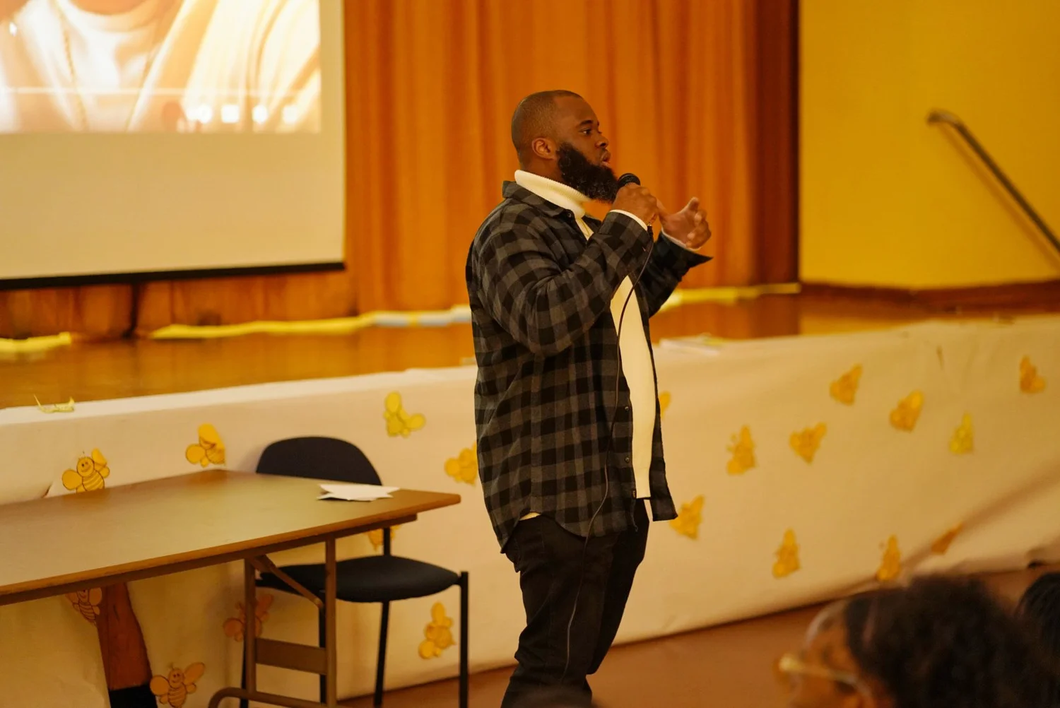 Man with a beard speaking into a microphone in a room 