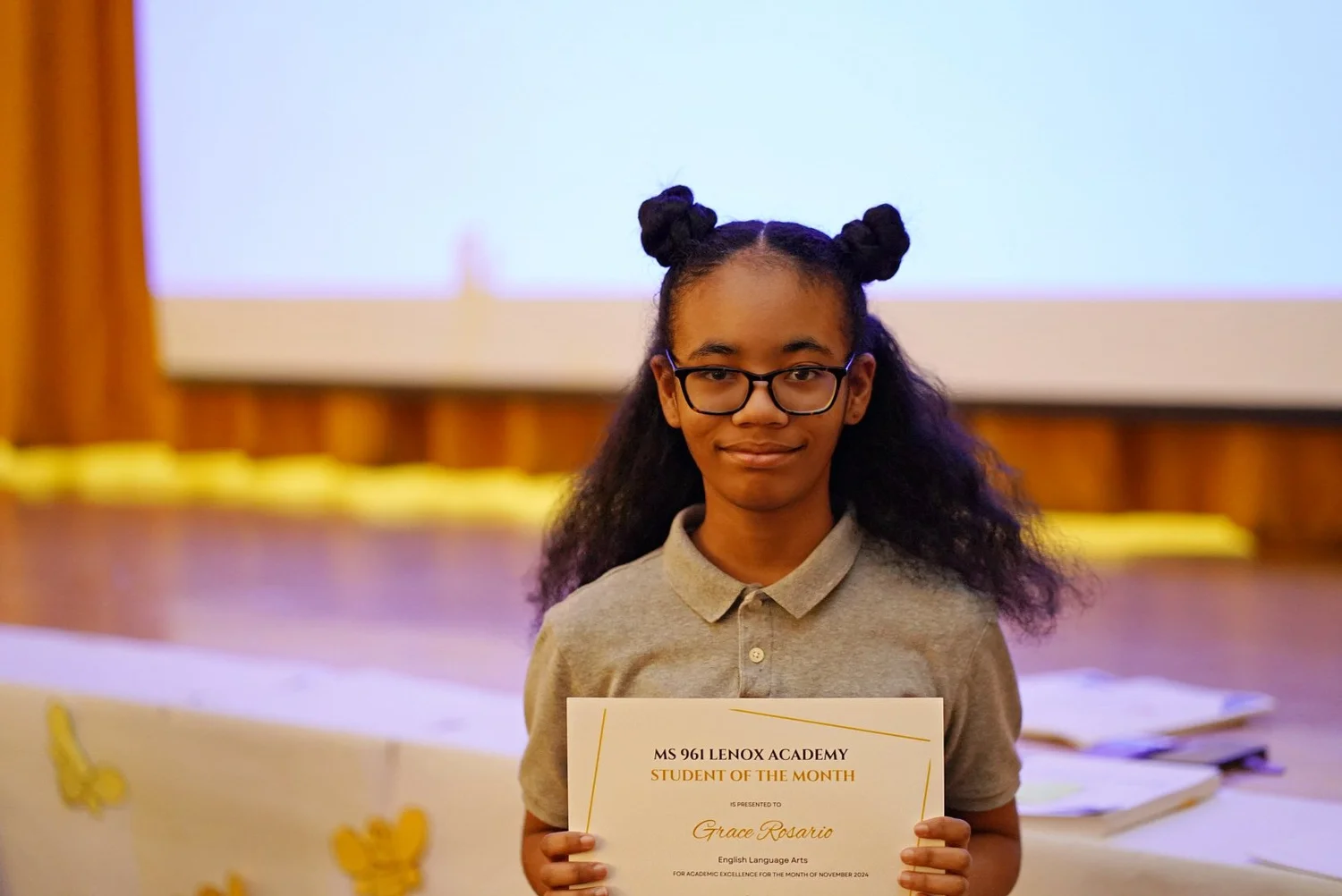 Student with glasses holding a certificate 