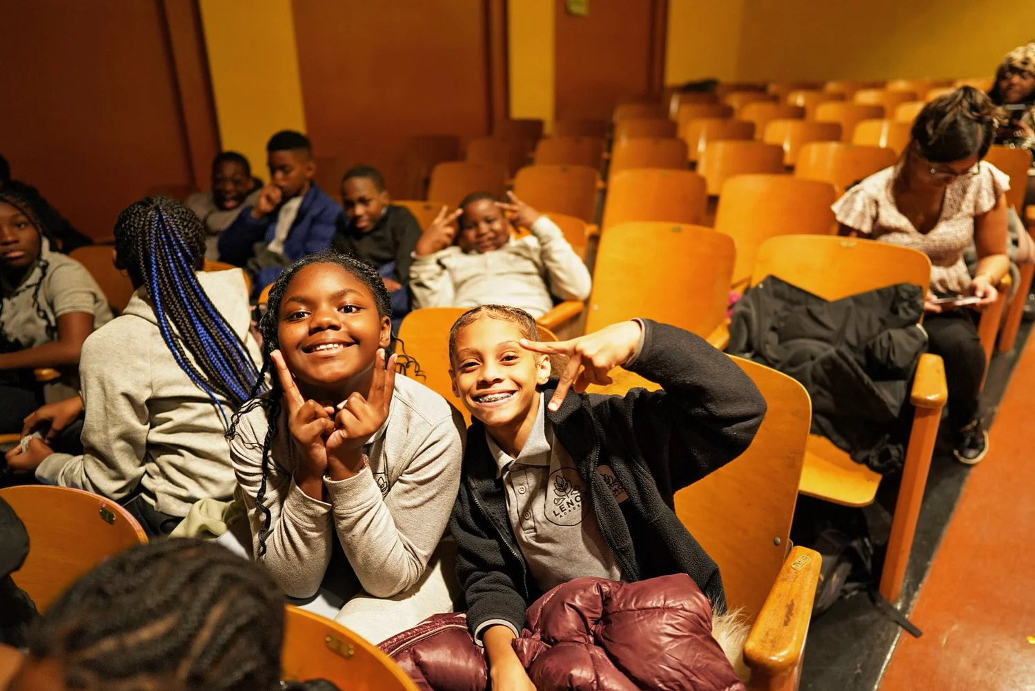 Two smiling children sitting in auditorium chairs