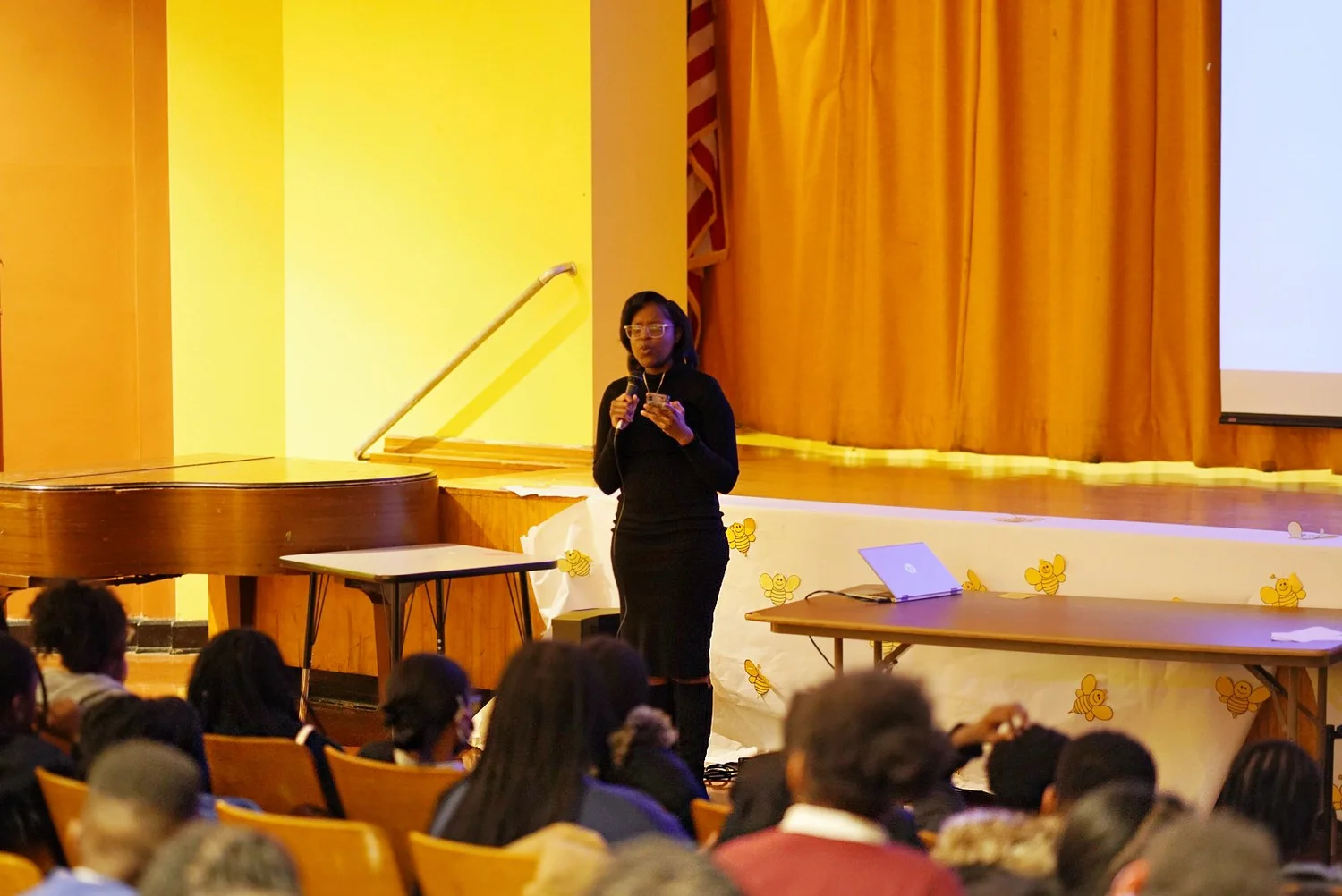 A woman in a black dress speaking into a microphone