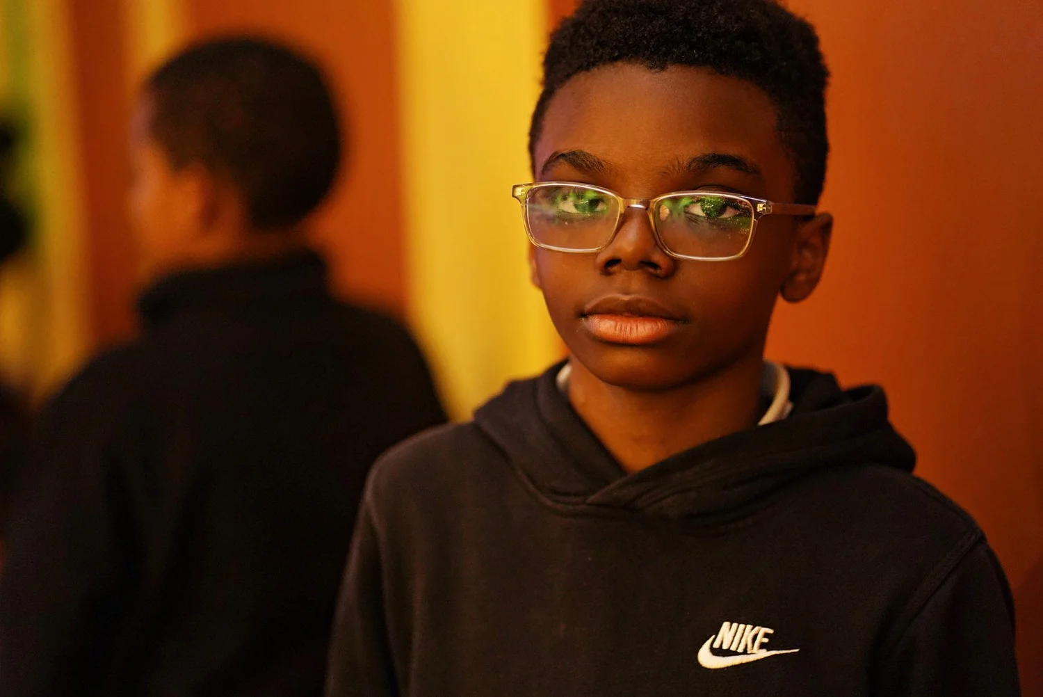 Young boy wearing glasses and a black Nike hoodie 