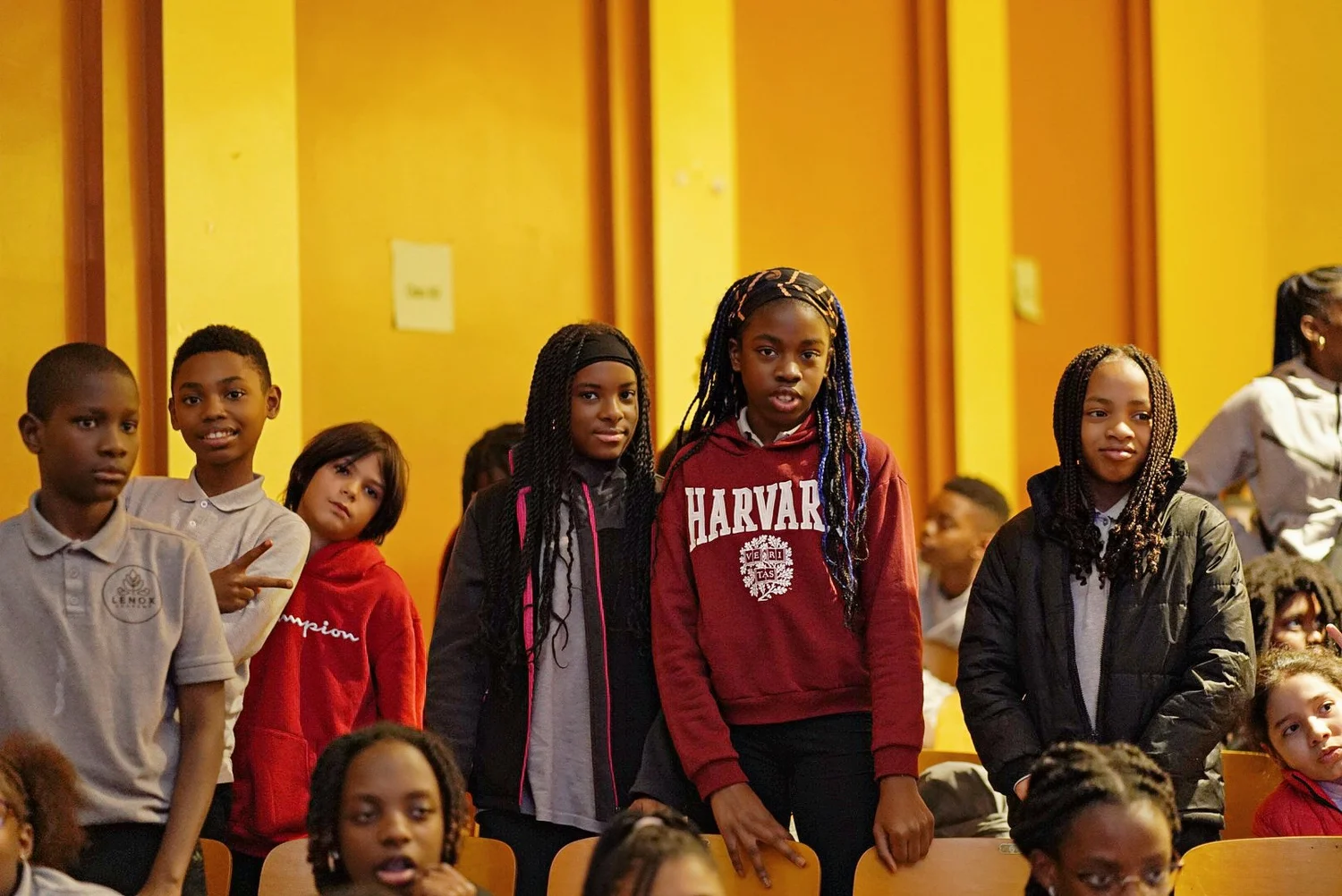 Group of diverse children standing indoors in front of yellow walls