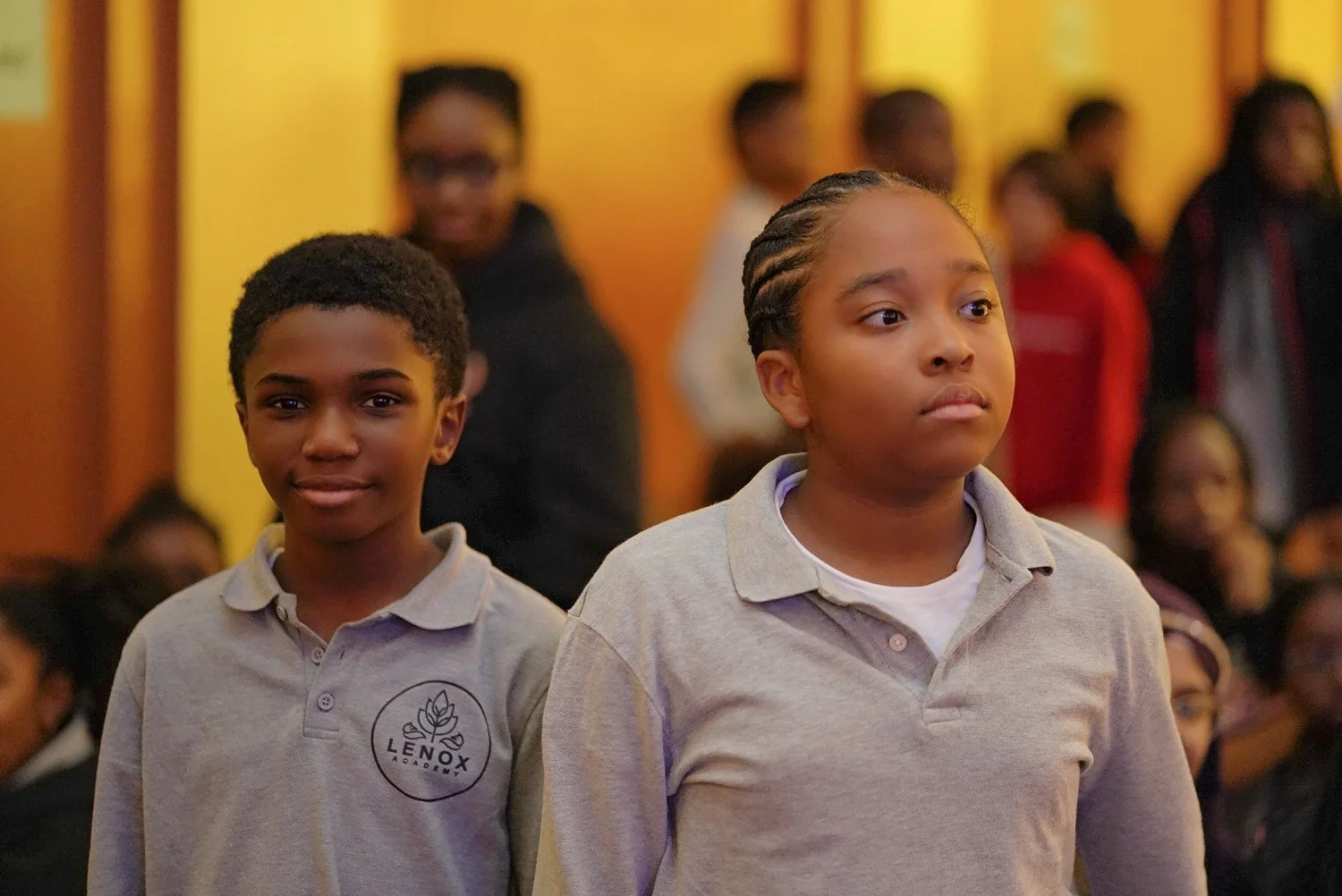 Two students in Lenox Academy gray polo shirts standing indoors