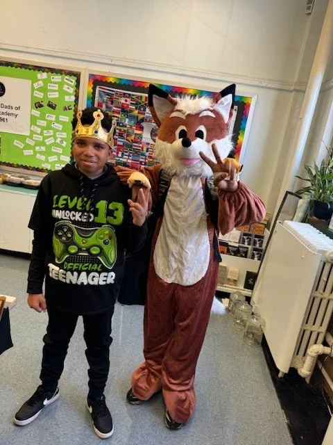 A boy wearing a crown and a black hoodie with a green game