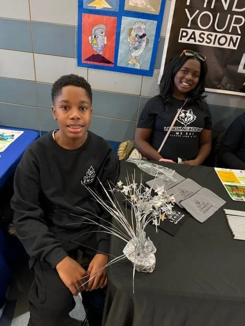Two students sitting behind a table with brochures 