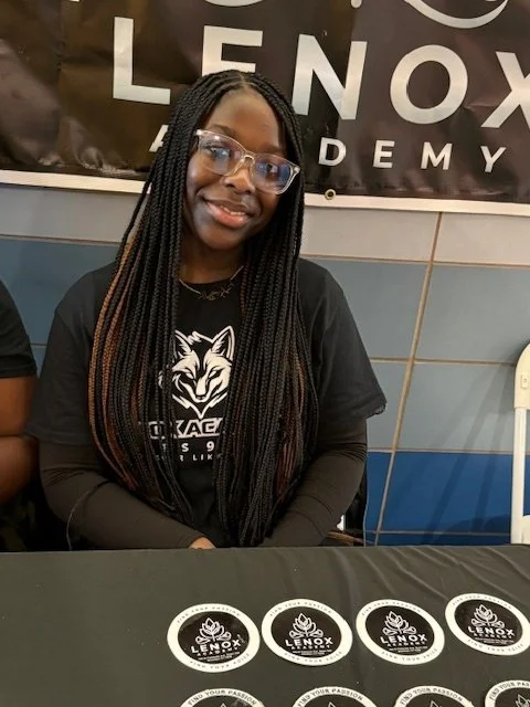 A young woman with long braided hair and glasses smiling
