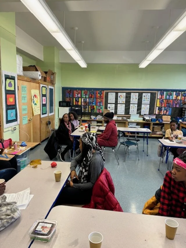 People sitting at tables in a classroom with colorful 