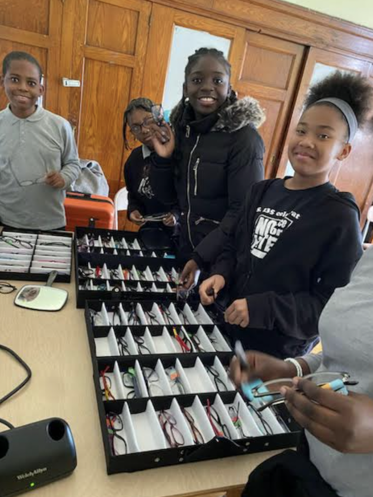 Group of smiling young people standing behind trays filled 