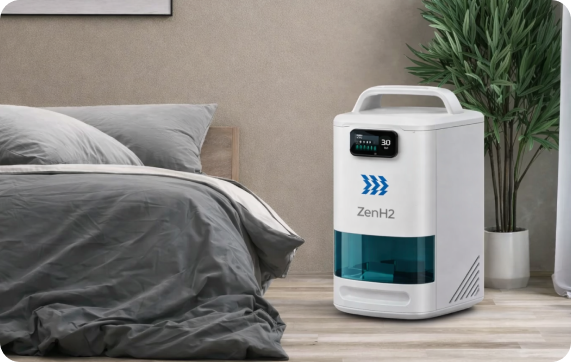 ZenH2 hydrogen inhalation machine placed on a wooden floor next to a bed with grey bedding and a potted plant in a modern bedroom.