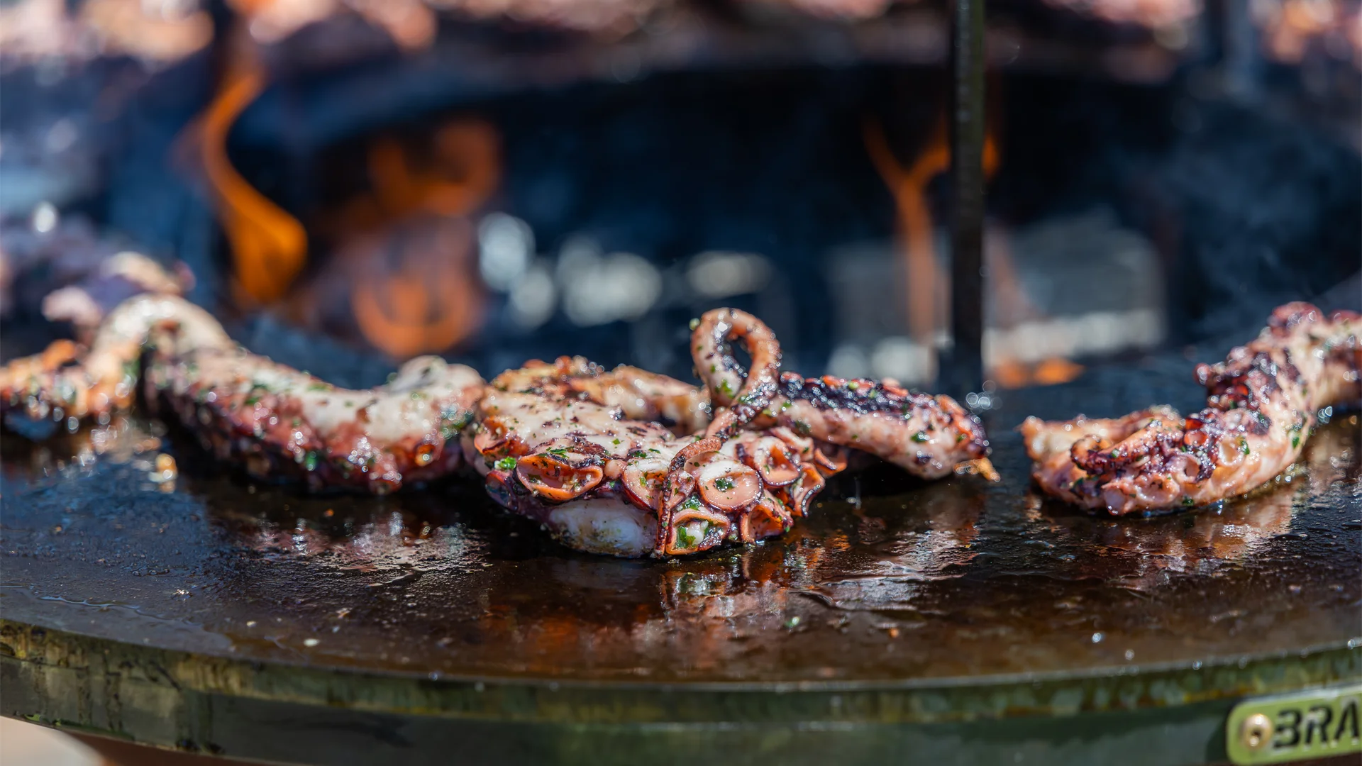 La cuisson d'un poulpe tendre au brasero pour un buffet extérieur haut de gamme par La Cantine en Folie.