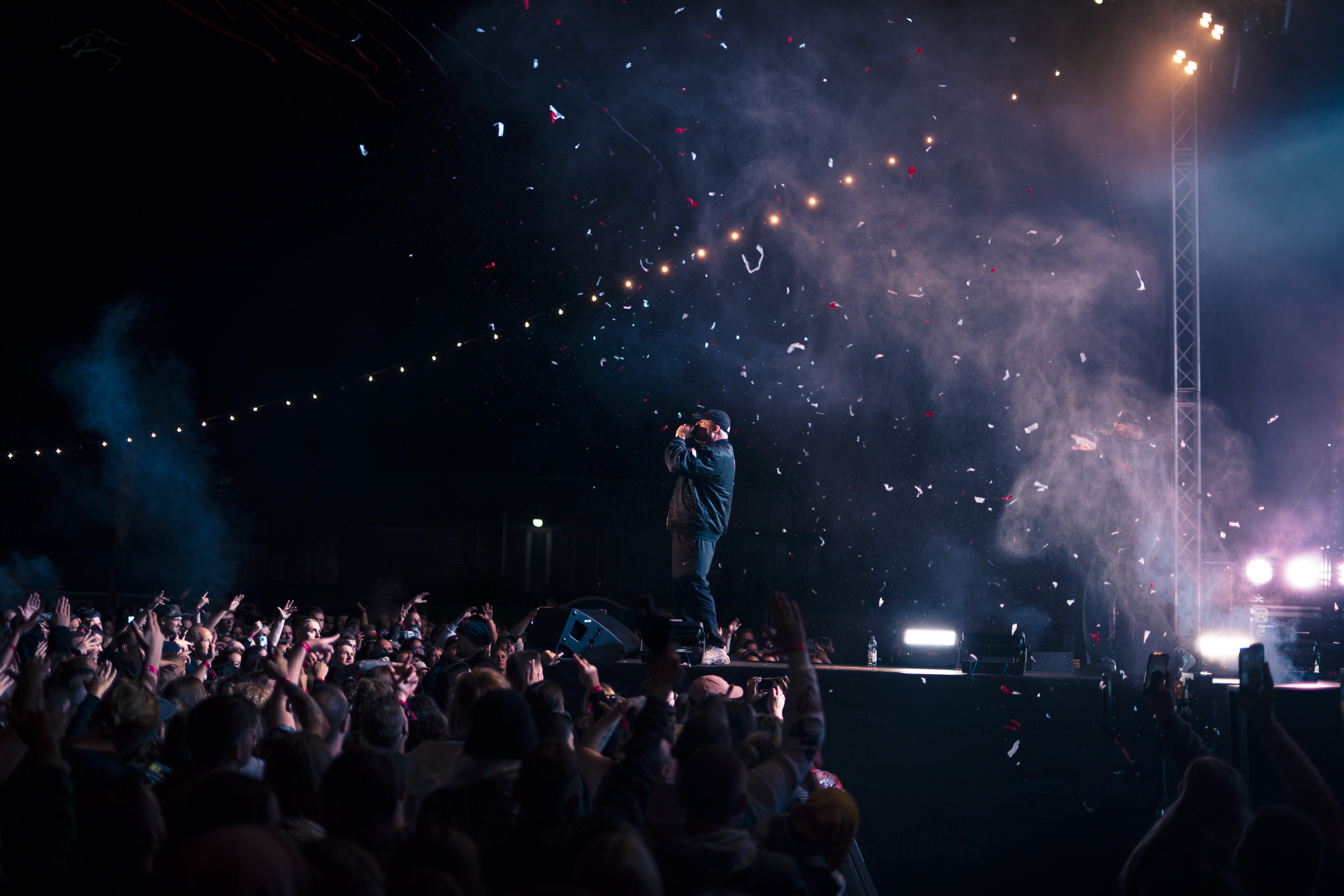 Kool Savas live auf einer Festivalbühne mit Konfetti-Effekt während eines Auftritts